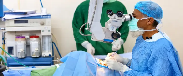 Surgeon performing eye surgery under an operating microscope