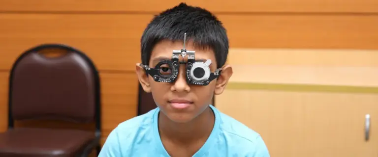 Schoolboy having his vision tested with a trial frame